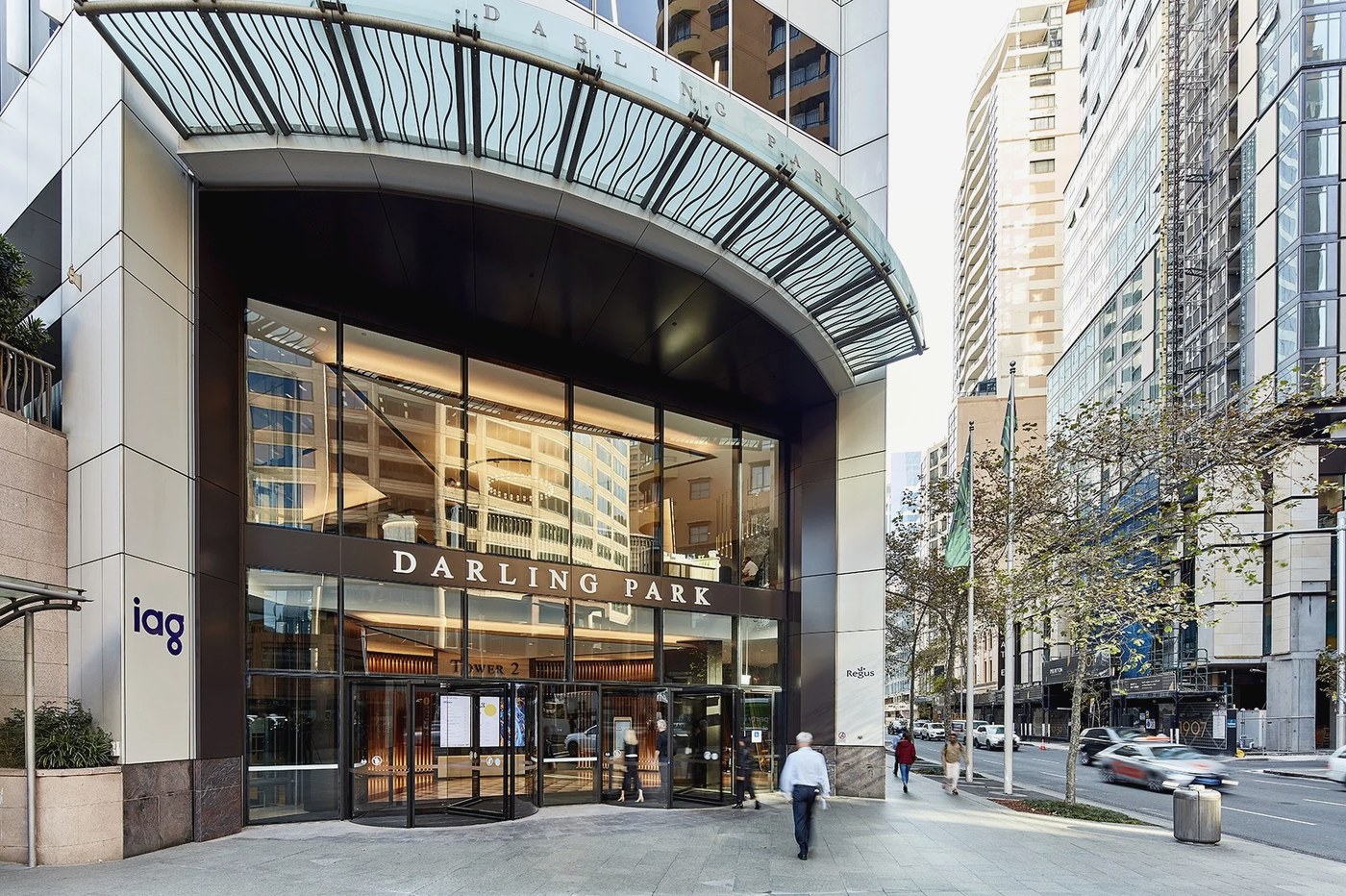 The glass entrance of Darling Park Tower 2 on Sussex Street, warm lobby light behind the facade