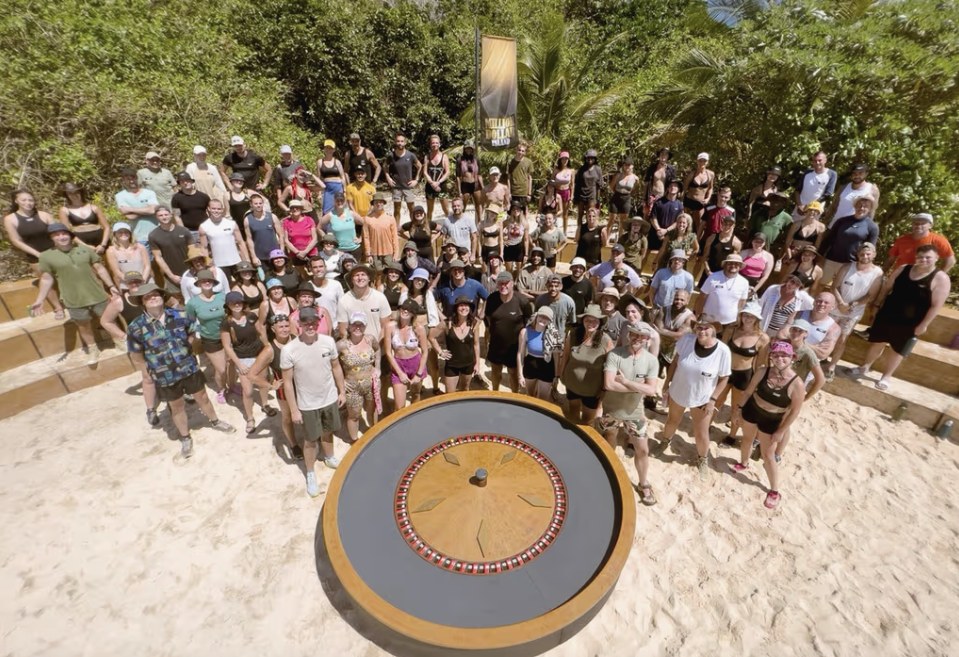 One hundred contestants gathered around the golden wheel on the island beach, jungle behind them