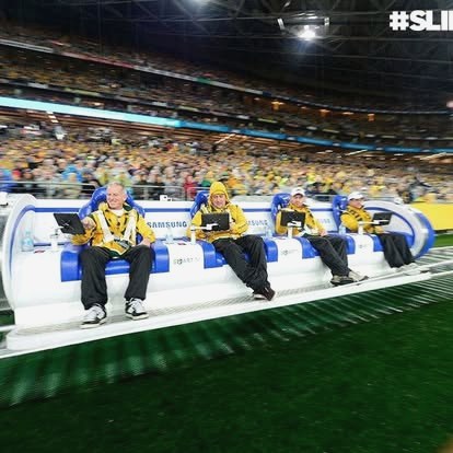 Fans riding the Samsung Slideliner couch with tablets in hand, a packed stadium bowl behind them