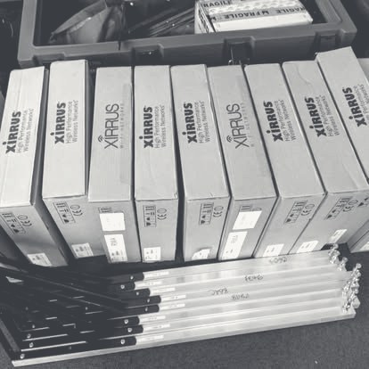 Rows of boxed wireless access points stacked in road cases during bump-in, graphite monochrome